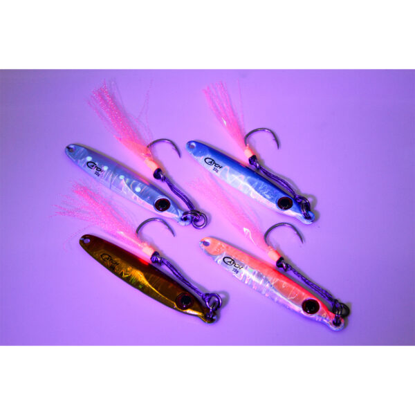 Check out this eye-catching setup: five vivid fishing lures decked out in metallic finishes and tassels, featuring the ultra-sleek Catch Pocket Rocket Tungsten Micro Jig, all artfully displayed on a striking purple canvas. Ready to make your tackle box pop with some serious flair?.